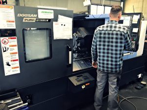 En tekniker som använder en doosan puma gt2600lm cnc-svarv i en industriell miljö.